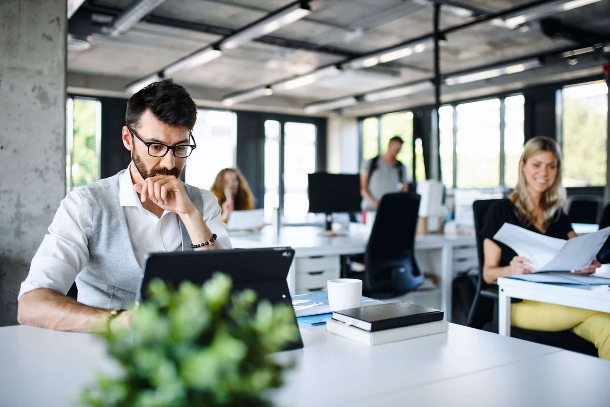 A manager reflecting in a bright, active workplace